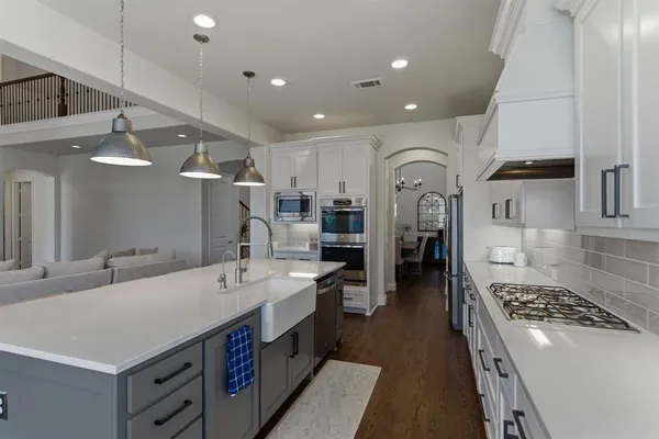 a large white kitchen with stainless steel appliances granite countertop a sink and cabinets