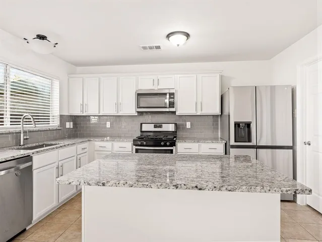 a kitchen with kitchen island granite countertop a stove sink and microwave