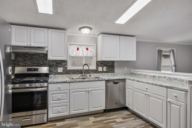 a kitchen with granite countertop a sink stove and cabinets