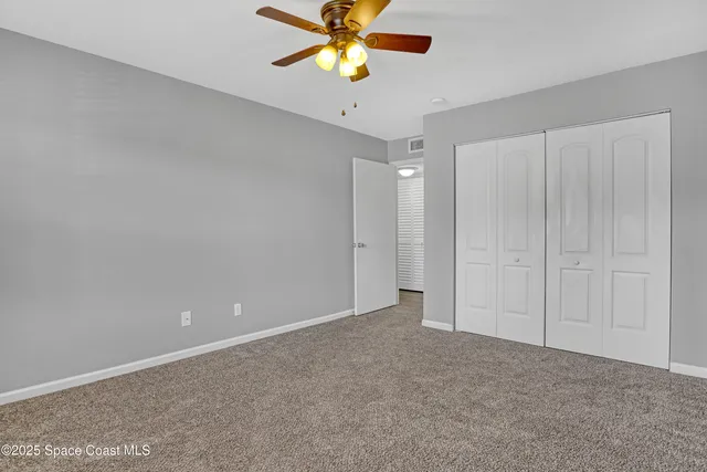 a view of an empty room and chandelier fan