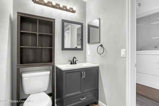 a bathroom with a toilet sink vanity and mirror