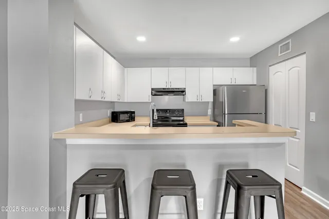 a kitchen with stainless steel appliances a sink a stove a refrigerator cabinets and a dining table