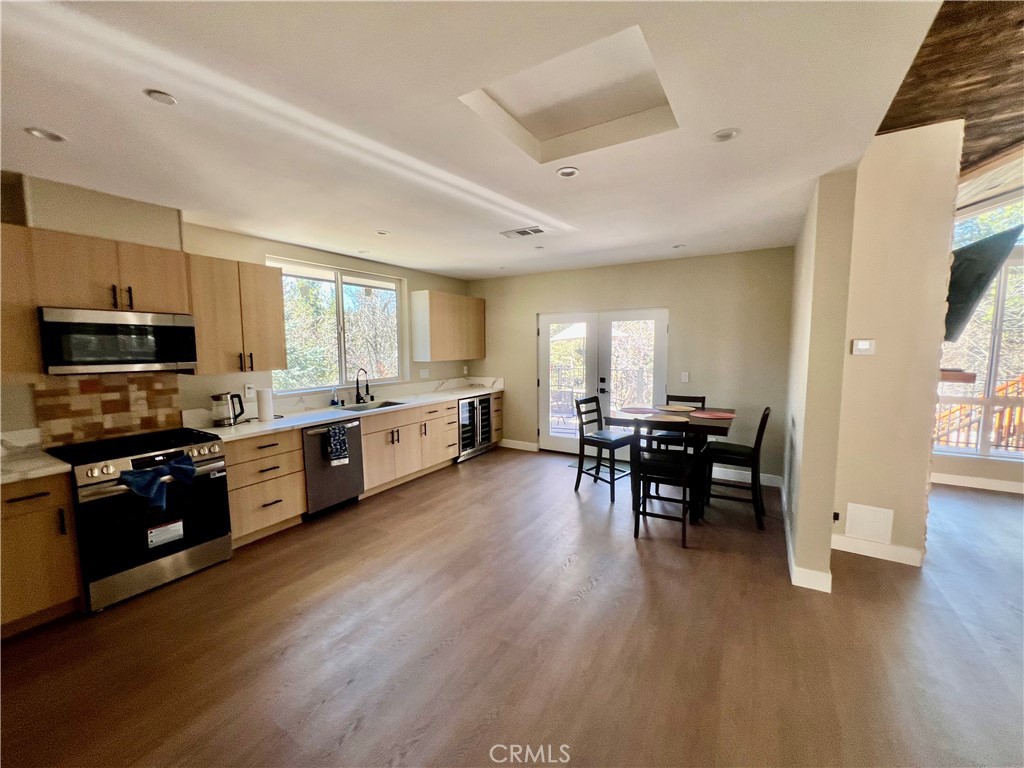 43290 Shasta Road Big Bear Lake, CA 92315 - Photo 10 of 36 a kitchen with stainless steel appliances kitchen island granite countertop a stove top oven a sink a dining table and chairs with wooden floor