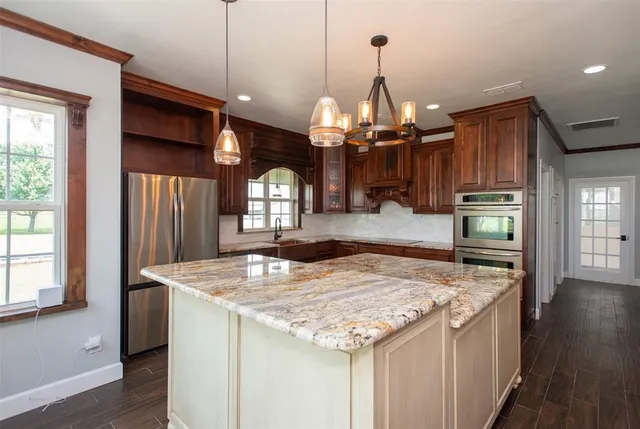a kitchen with kitchen island granite countertop wooden floor cabinets and stainless steel appliances