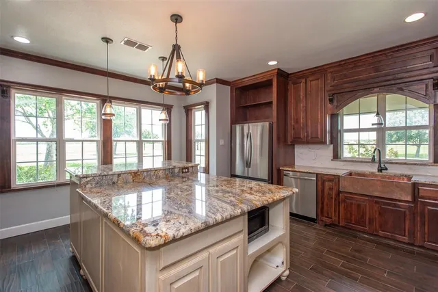 a kitchen with granite countertop cabinets a sink a window and stainless steel appliances