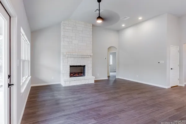 a view of an empty room with wooden floor fireplace and a window