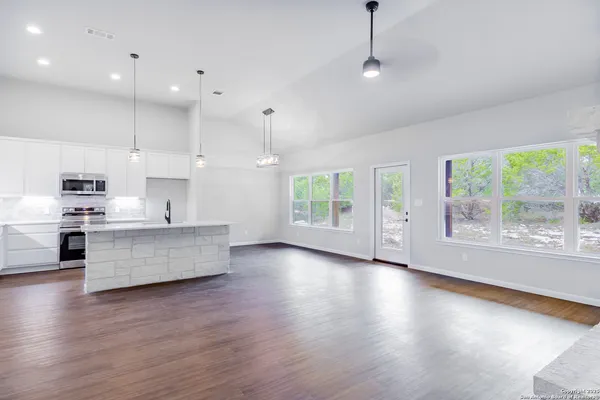 a large kitchen with kitchen island a island a stove a wooden floor and a large window