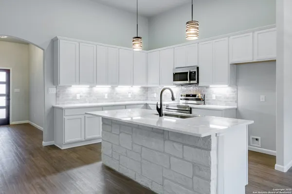 a kitchen with kitchen island granite countertop a sink stainless steel appliances and white cabinets