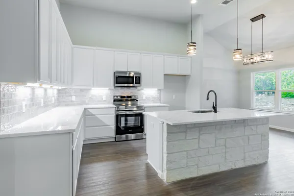 a kitchen with kitchen island granite countertop a sink cabinets and stainless steel appliances