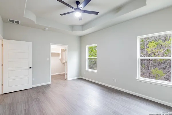 a view of an empty room with a window and wooden floor