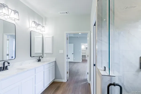 a spacious bathroom with a double vanity sink a mirror and shower