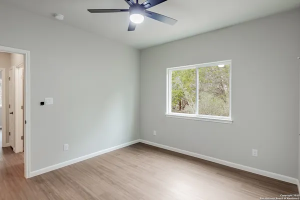 an empty room with a window and a ceiling fan