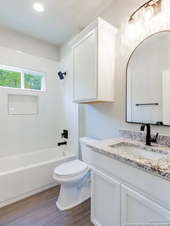 a bathroom with a granite countertop toilet sink and mirror