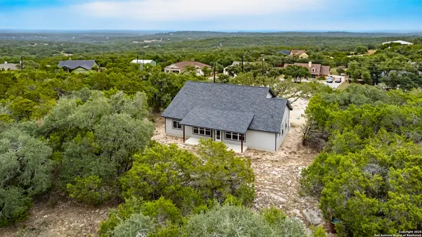 an aerial view of residential houses with outdoor space and trees