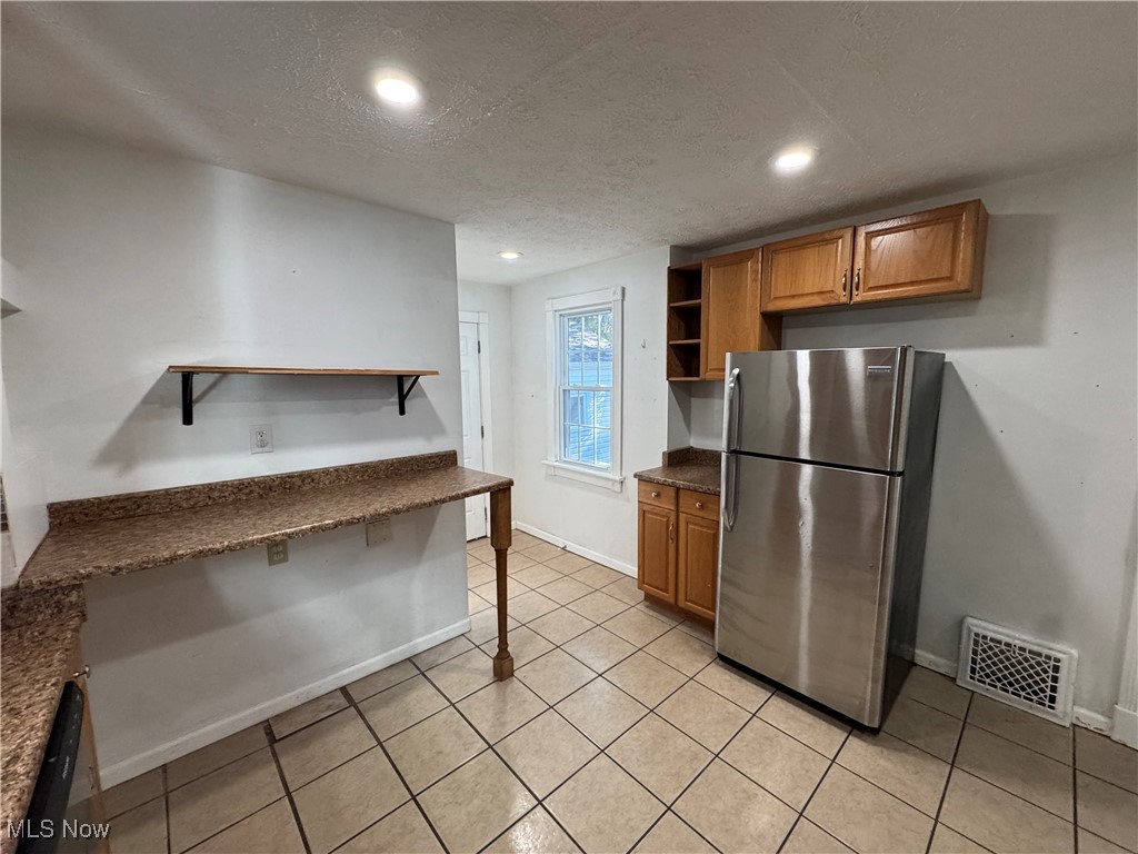 2425 7th Street Northwest Canton, OH 44708 - Photo 9 of 19 Kitchen featuring open shelves, brown cabinets, freestanding refrigerator, a textured ceiling, and light tile patterned floors