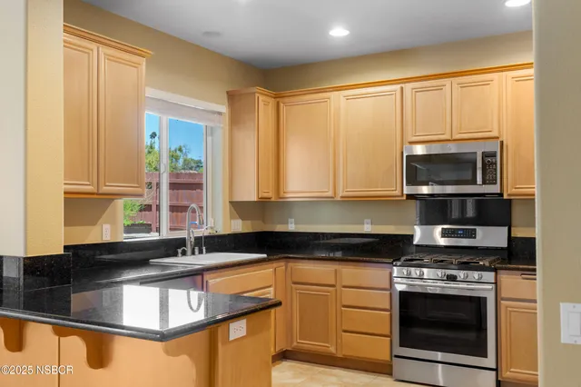 a kitchen with stainless steel appliances granite countertop a stove a sink and a microwave