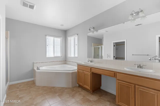 a spacious bathroom with a double vanity sink mirror and bathtub
