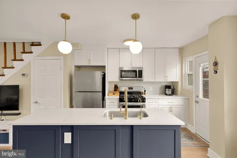 a kitchen with stainless steel appliances a refrigerator a sink dishwasher a stove a microwave oven with cabinets and wooden floor