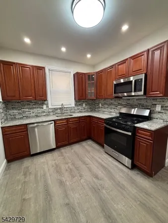 a kitchen with stainless steel appliances granite countertop wooden cabinets a stove a sink and a microwave