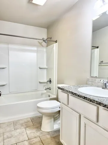 a bathroom with a granite countertop sink toilet mirror and a bathtub
