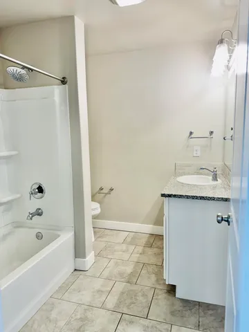 a bathroom with a granite countertop sink a toilet and shower