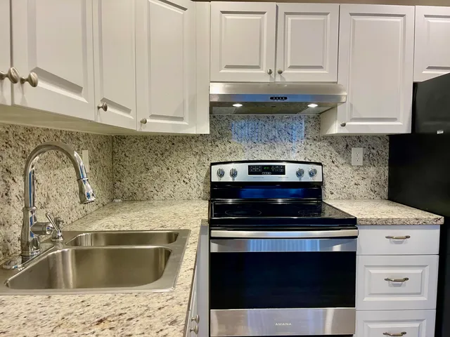 a kitchen with granite countertop white cabinets and stainless steel appliances