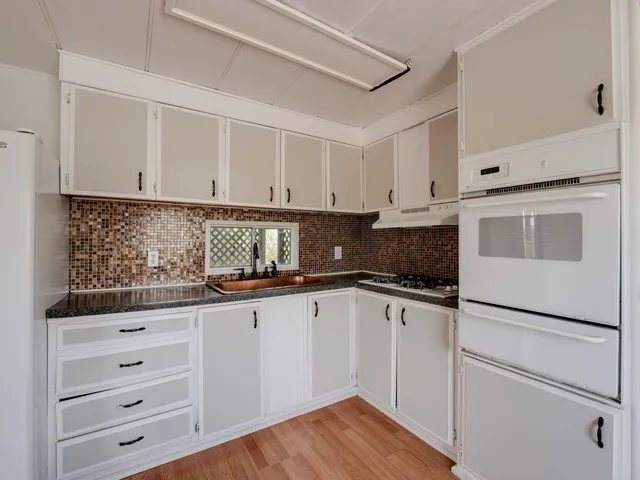 a kitchen with granite countertop white cabinets and white appliances