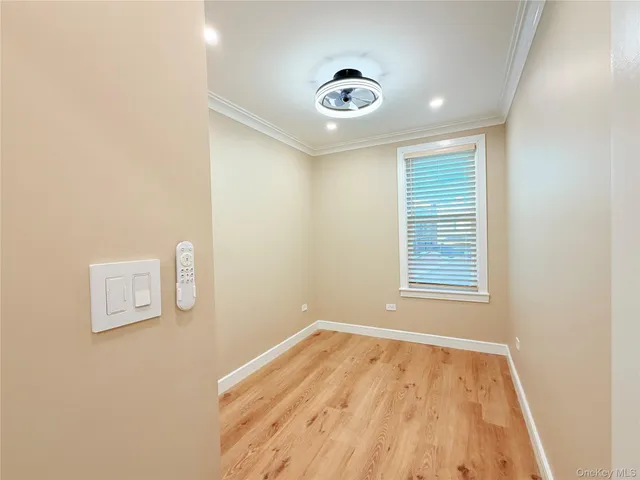 a view of empty room with wooden floor and fan