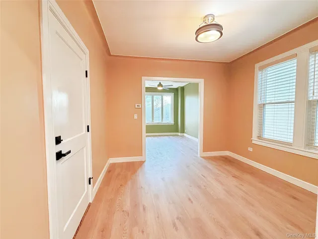 a view of a hallway with wooden floor and a bathroom
