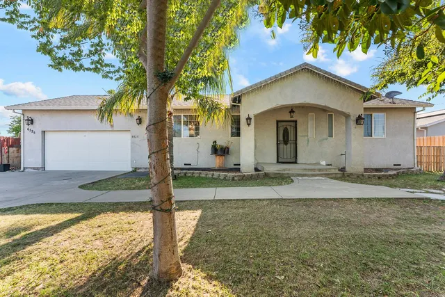 a view of a house with a yard and palm trees