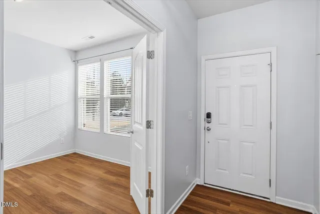 a view of an empty room with wooden floor and a window