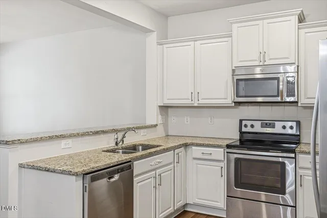 a kitchen with granite countertop a sink stove and microwave