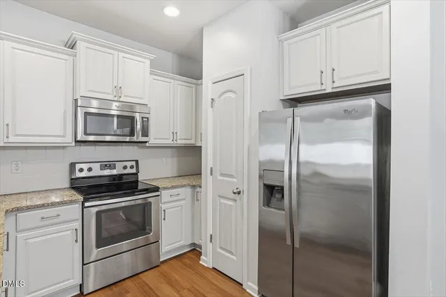 a kitchen with white cabinets and stainless steel appliances