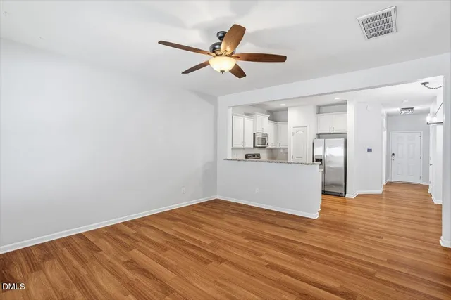a view of empty room with wooden floor and ceiling fan