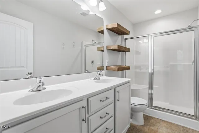 a bathroom with a sink toilet double vanity and shower
