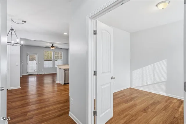 a view of a hallway with wooden floor and a bathroom