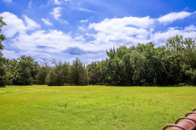 a view of a house with a big yard and large trees