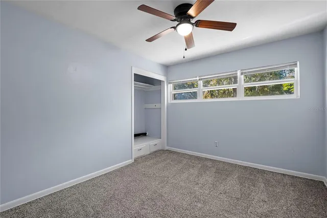 an empty room with ceiling fan and window