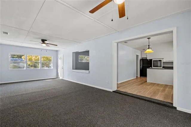 an empty room with windows and ceiling fan
