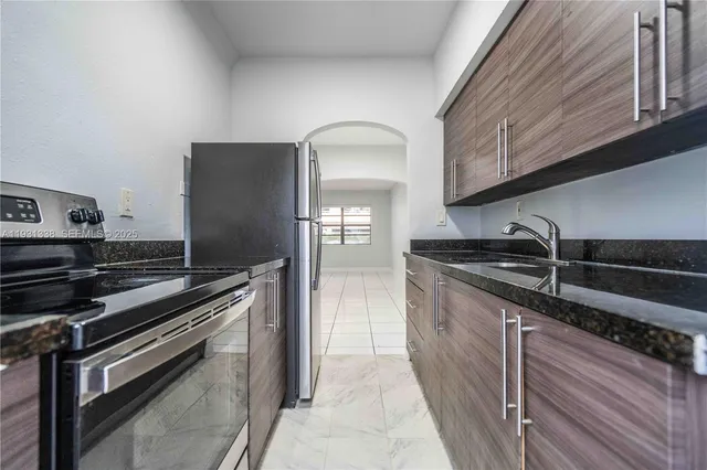 a kitchen with granite countertop a sink cabinets and stainless steel appliances