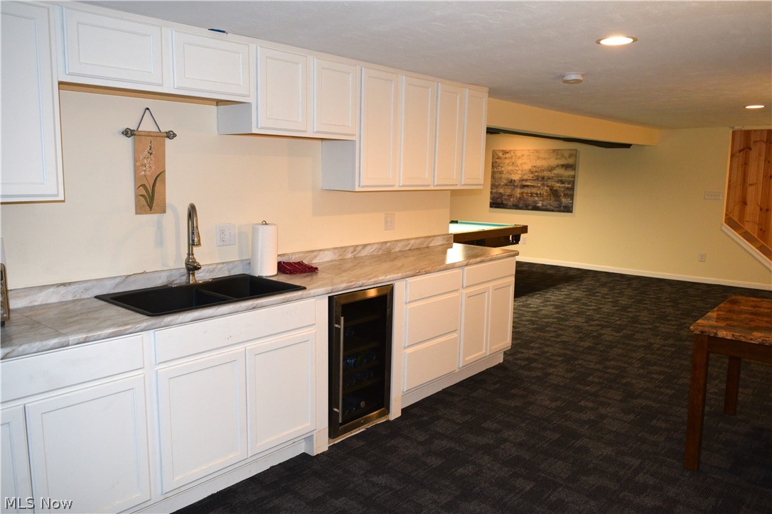3285 Hemphill Road Barberton, OH 44203 - Photo 32 of 50 Kitchenette featuring dark colored carpet, wine cooler, white cabinets, and sink