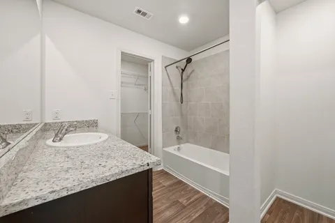a bathroom with a granite countertop sink and a bathtub
