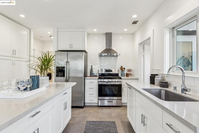 a kitchen with stainless steel appliances granite countertop a sink a stove and a refrigerator