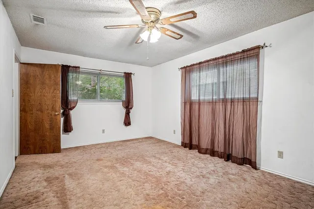 an empty room with windows and fan