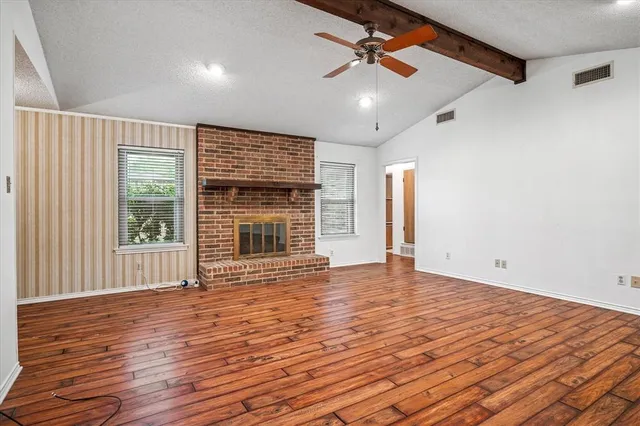 a view of an empty room with a window and wooden floor