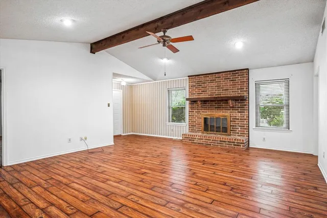 a view of empty room with wooden floor and fireplace