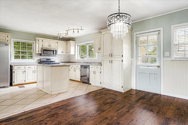 a kitchen with stainless steel appliances granite countertop a stove top oven a sink dishwasher and a refrigerator with wooden floor