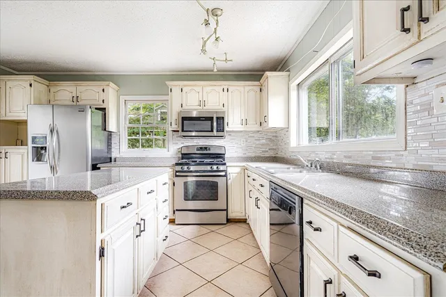 a kitchen with kitchen island granite countertop a sink appliances cabinets and a counter top space