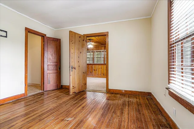 an empty room with wooden floor and windows