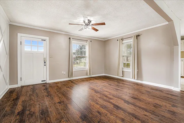 a view of an empty room with wooden floor and a window